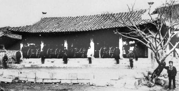 Four Gatling guns and a line of Japanese troops drawn up before a tiled-roof building at Ganghwa, 1876 Kuroda mission.